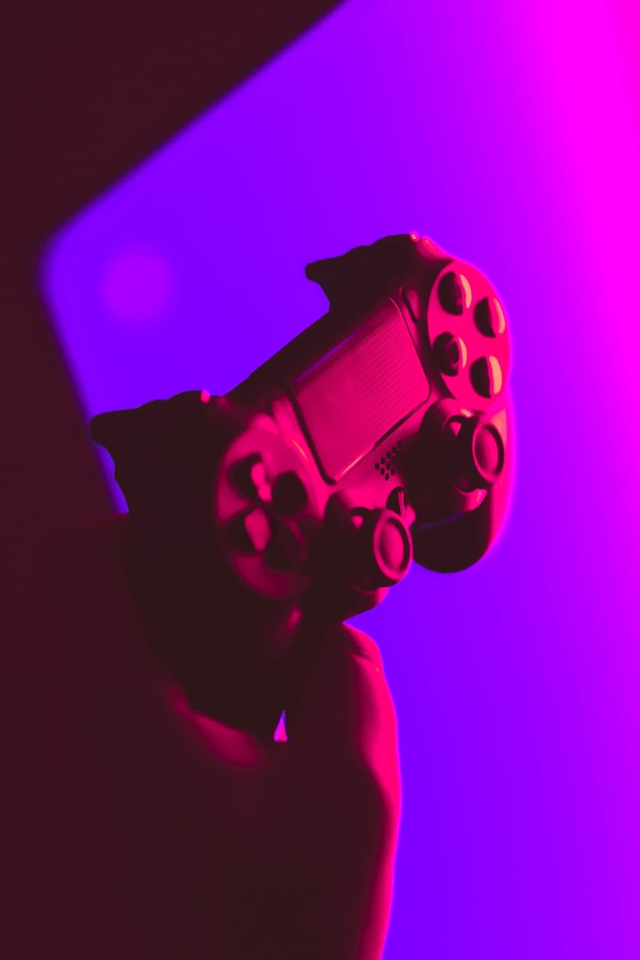 A game controller lit by vibrant pink and purple light